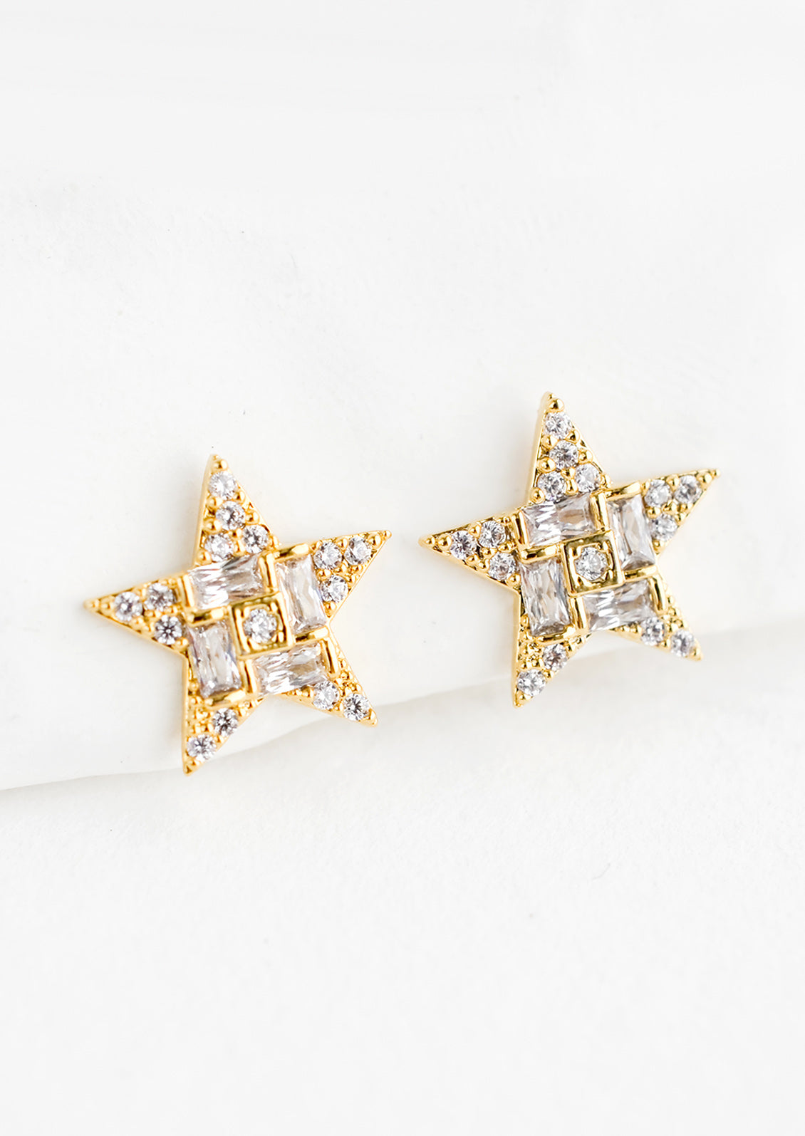 A pair of gold star shaped stud earrings with crystal pave detailing.