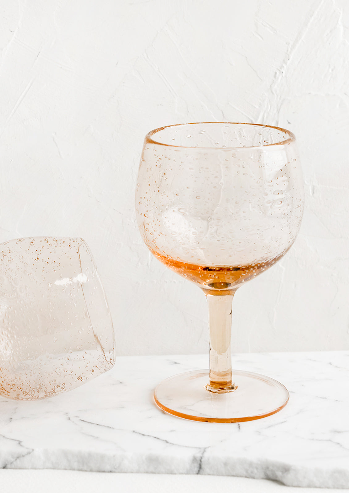 A tall wine glass in rose seeded glass.