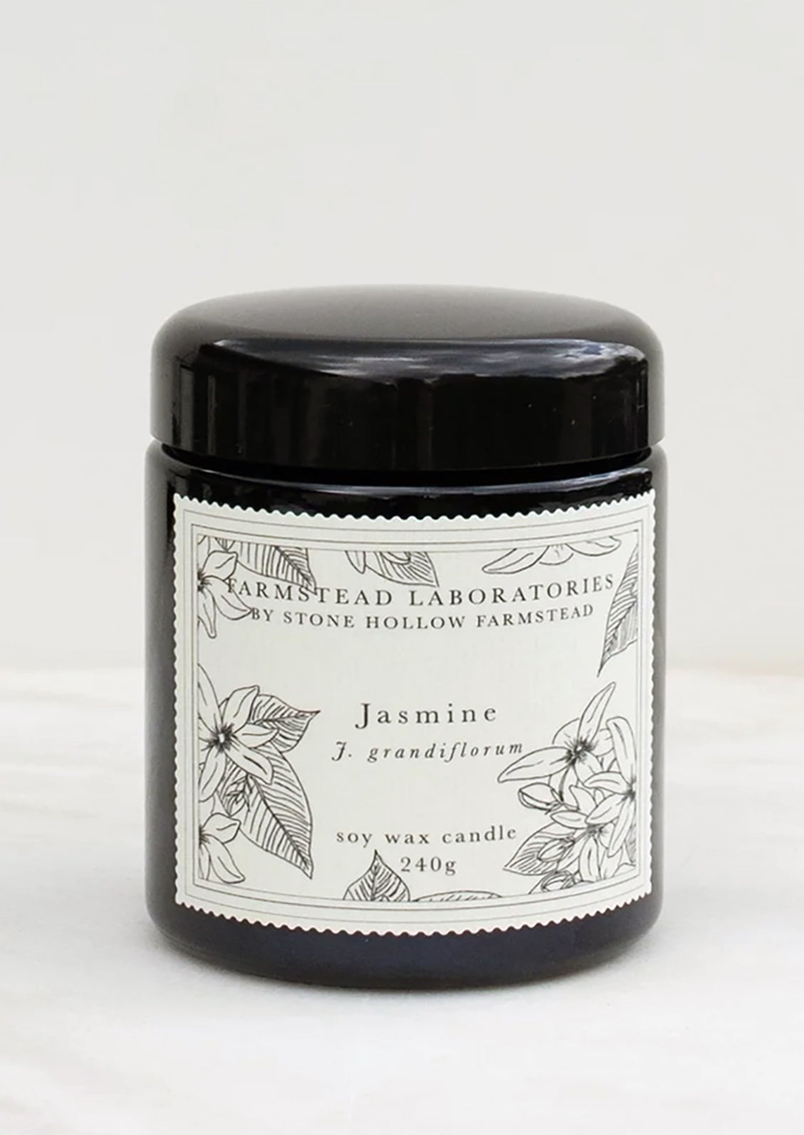 A jasmine scented candle in black jar with black and white botanical label.