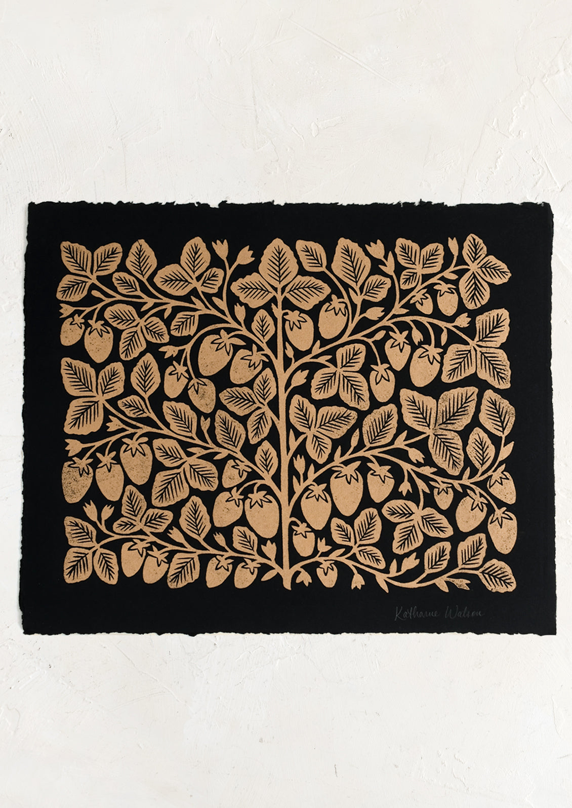 A black deckled edge paper with woodcut strawberry print in gold ink.