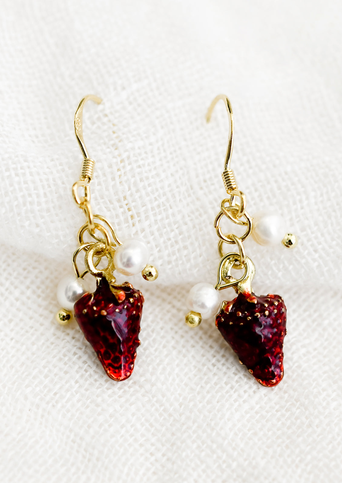 A pair of earrings with strawberry and pearl beads.