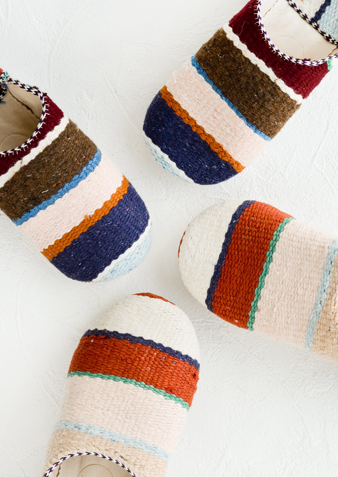 An assortment of house slippers made from wooly multicolor striped fabric.