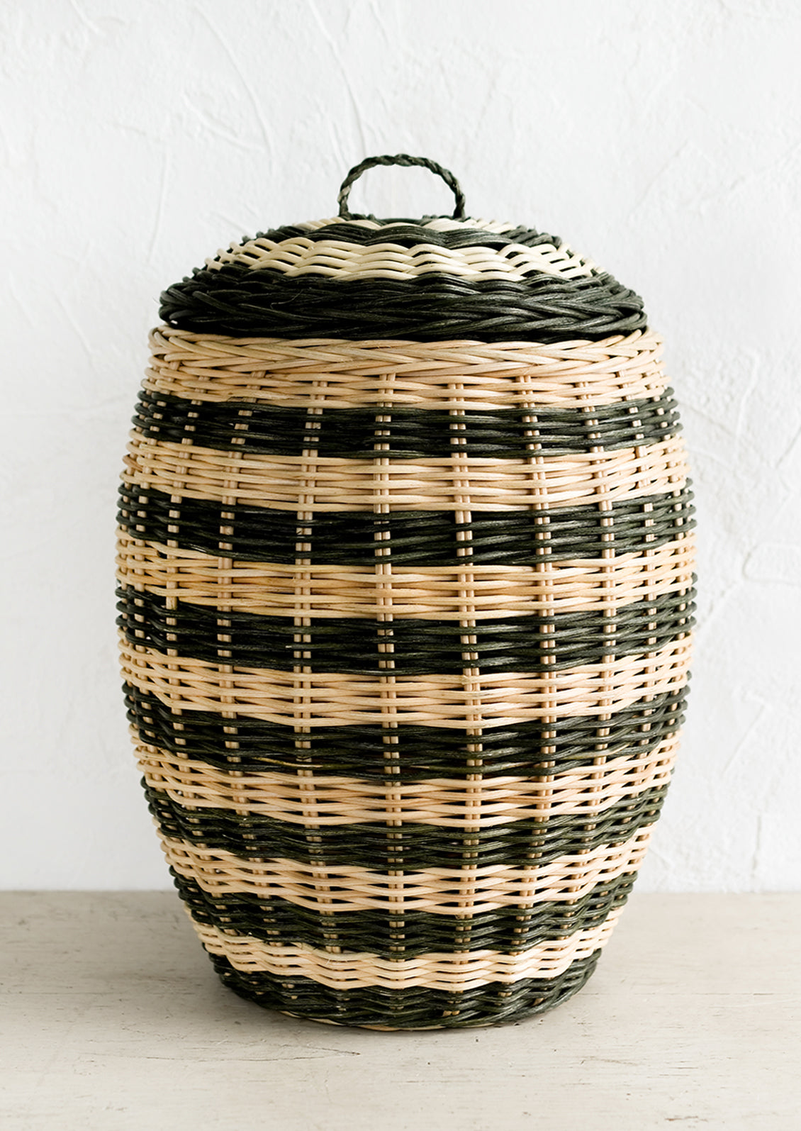 A tall hive shaped lidded basket in natural and dark green stripes.