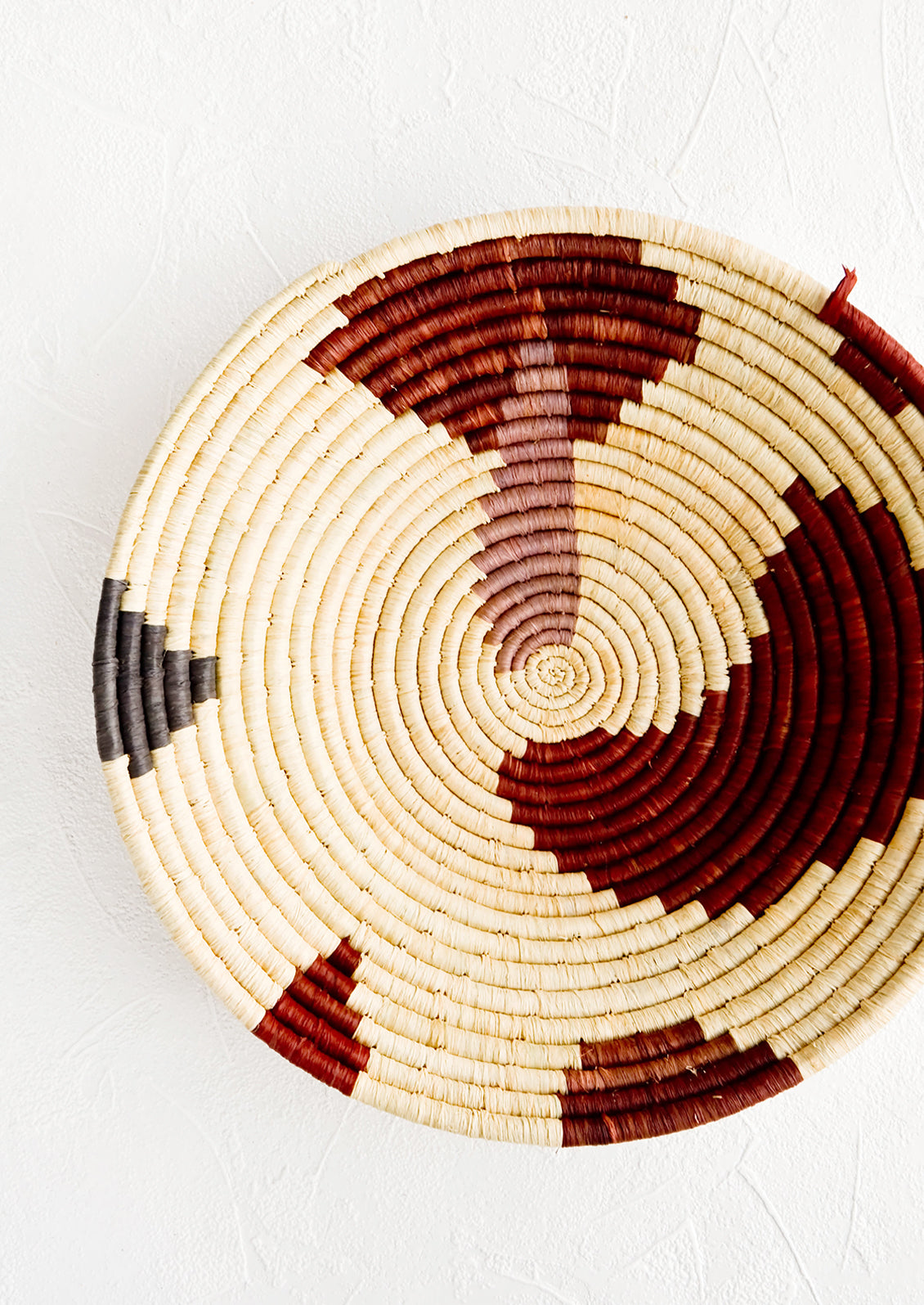 Shallow woven raffia bowl with abstract pattern in lavender, wine and charcoal