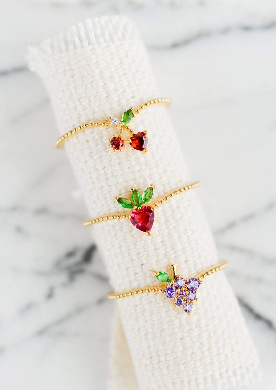 Fruit themed crystal and gold rings.