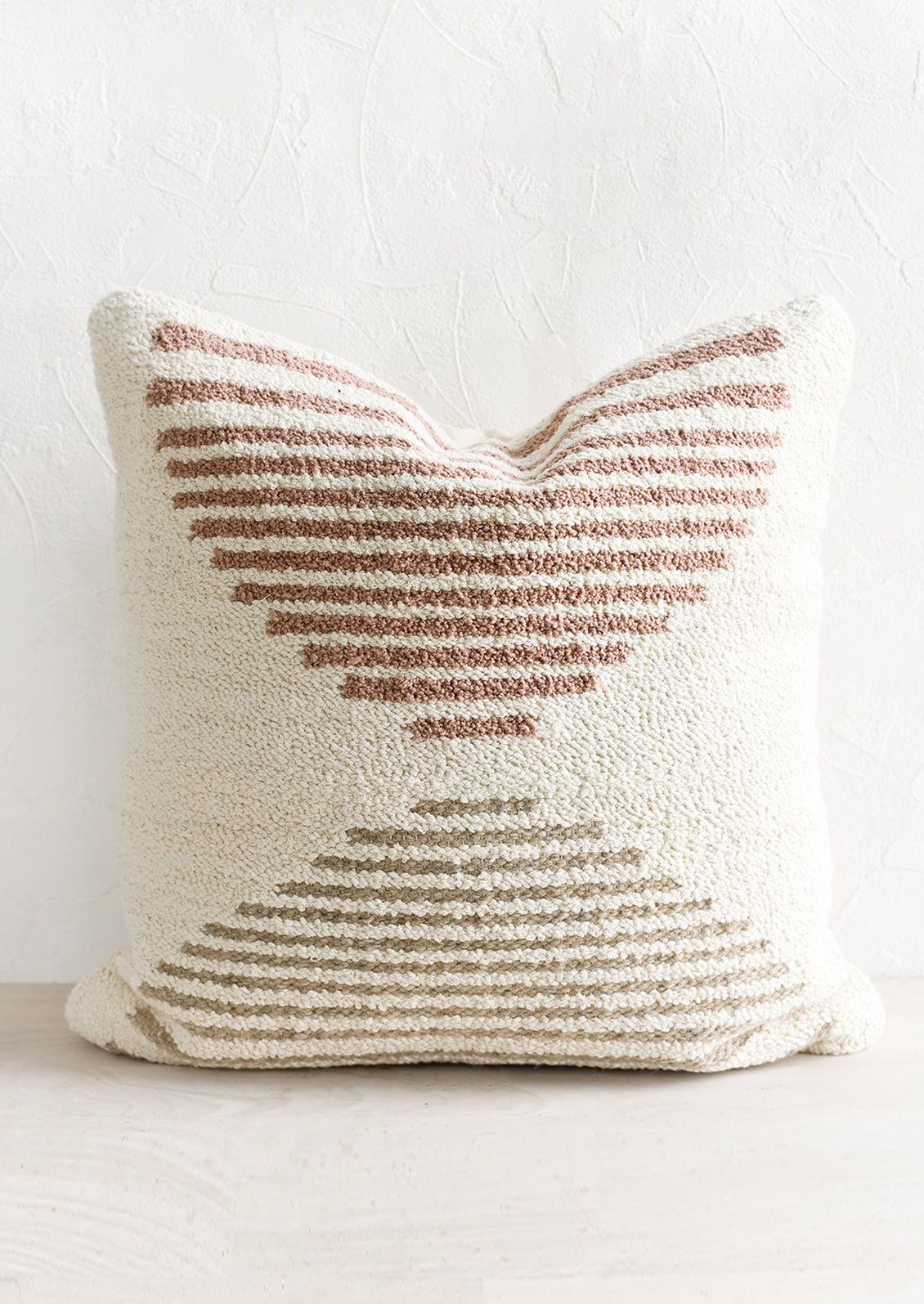 A tufted pillow in ivory with mauve and taupe geometric "horizon" design.