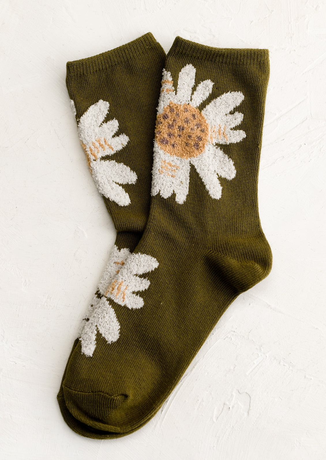 A pair of olive colored socks with fuzz textured, white-colored flowers.
