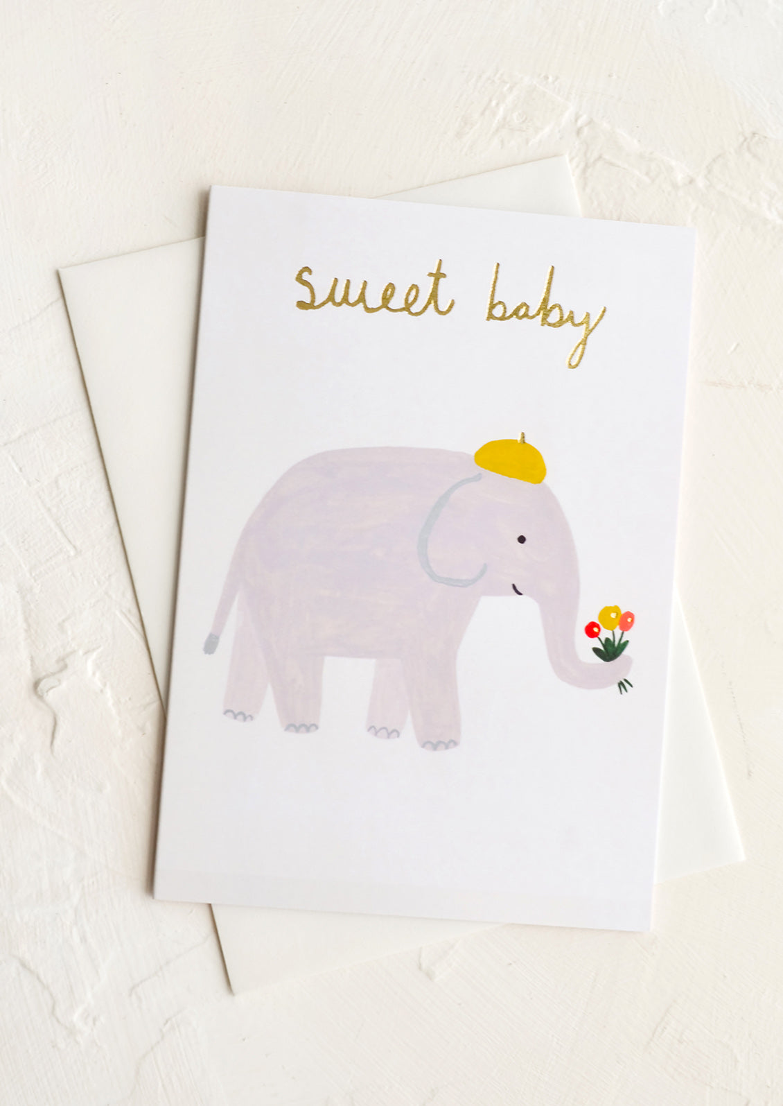 A greeting card with illustration of an elephant holding flowers in its trunk, text at top reads "sweet baby".