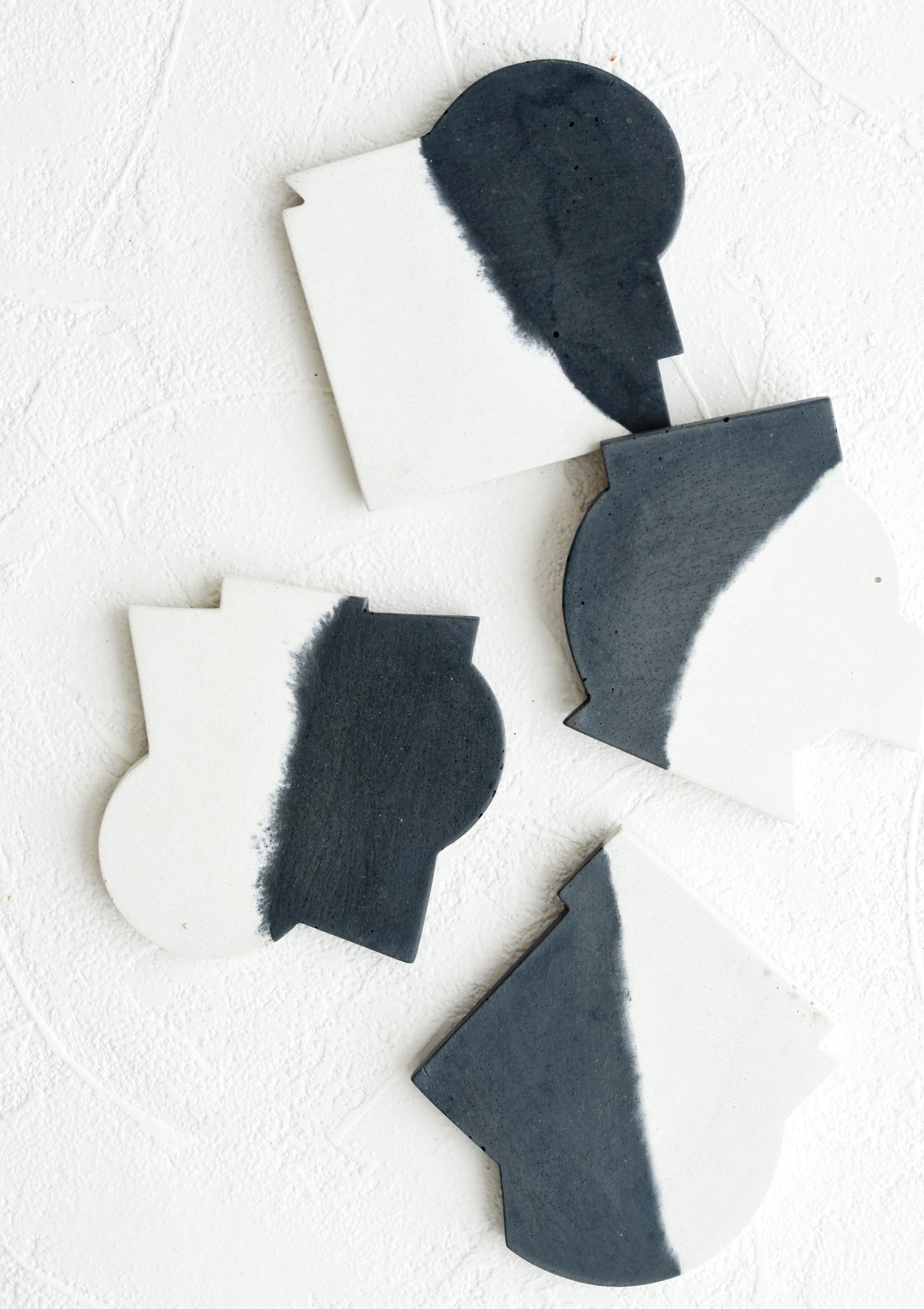 Four concrete coasters in black & white color with unique abstract shapes.