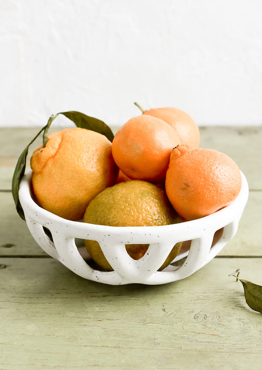 A white ceramic fruit bowl with clementines.