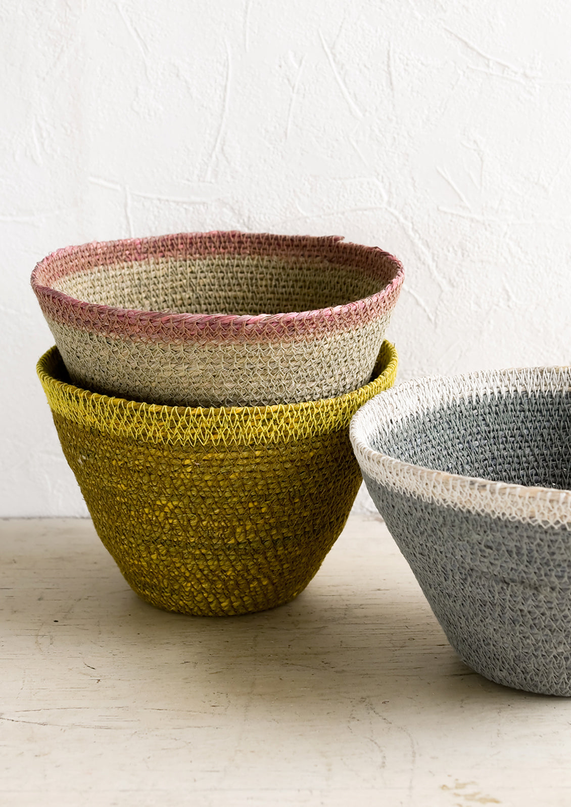 Three tapered storage baskets in assorted colors.