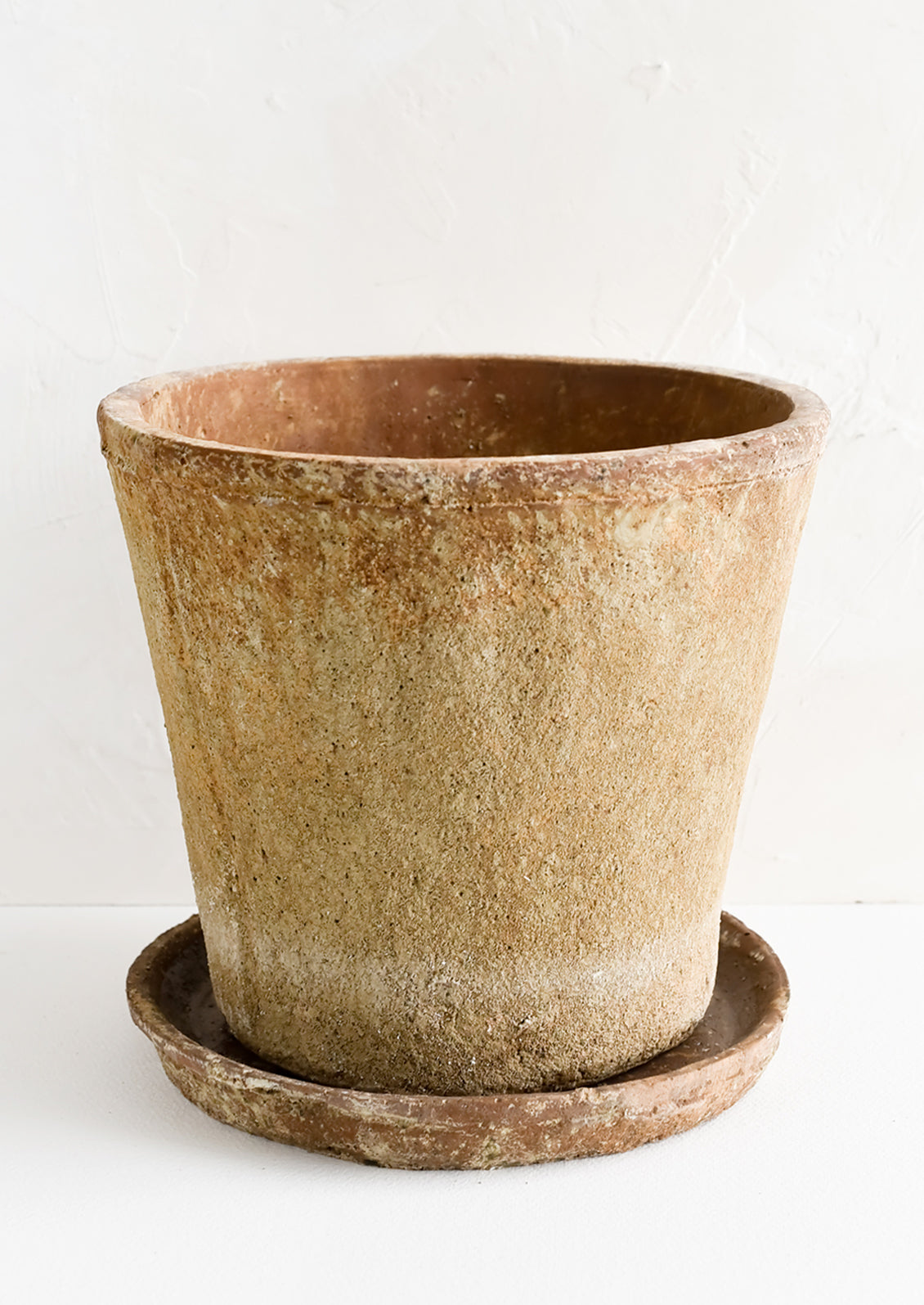 A rustic, heavily textured terracotta clay planter with saucer.