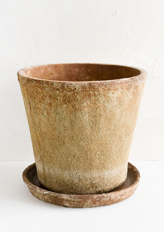 A rustic, heavily textured terracotta clay planter with saucer.