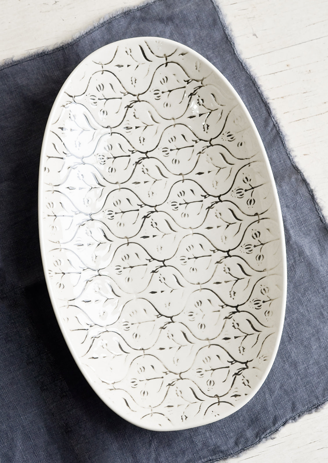 A smaller oval shaped ceramic platter with black and white textile pattern.