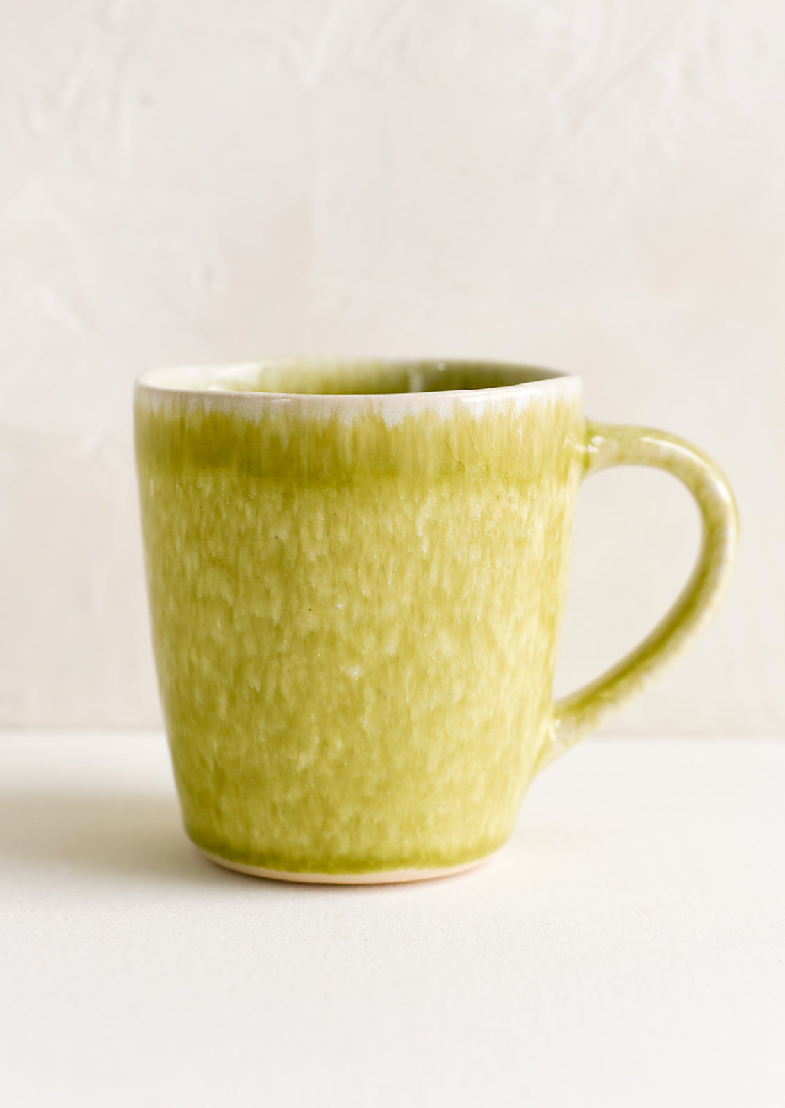 A glossy glazed chartreuse ceramic mug.