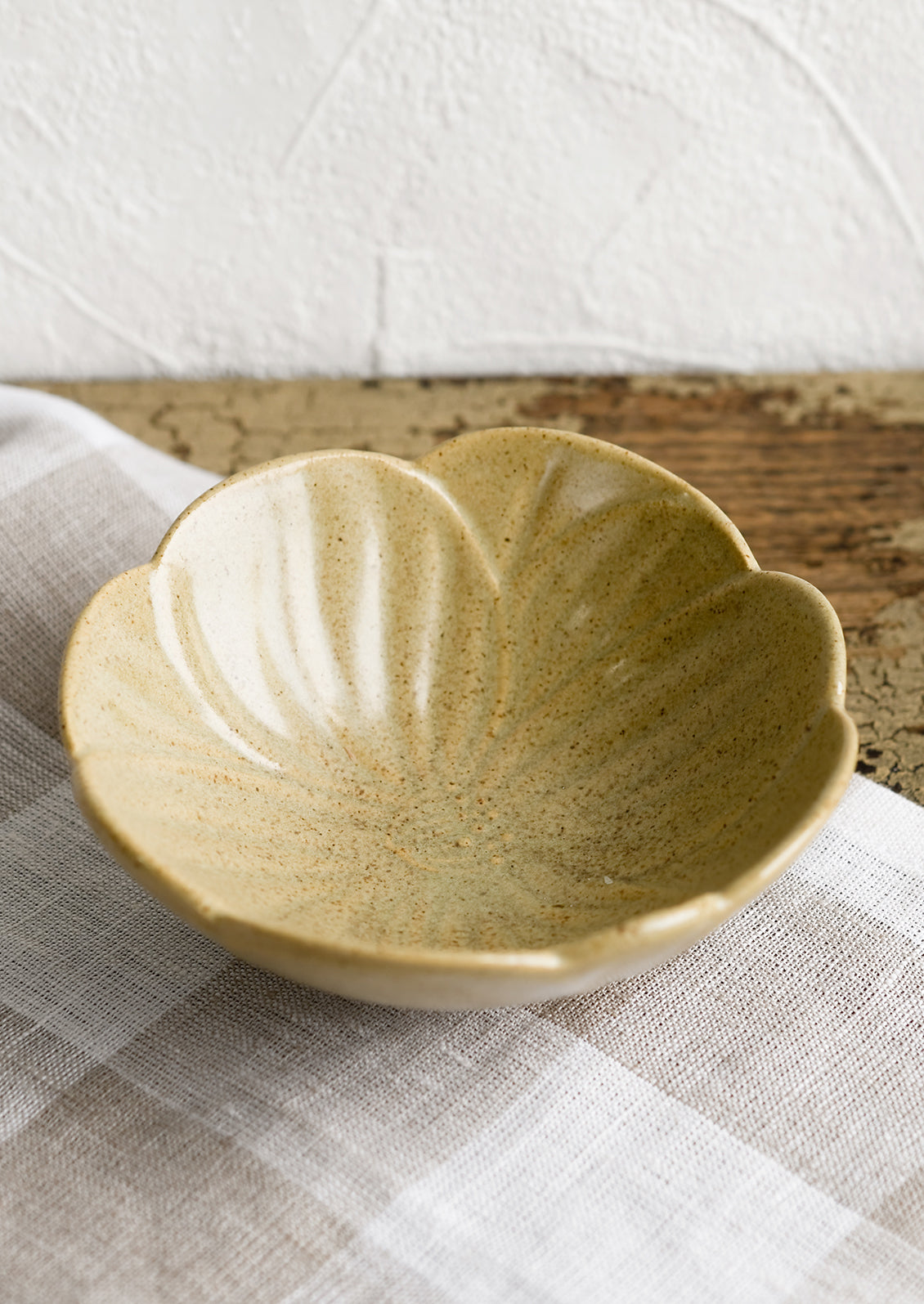 A tan ceramic flower shaped bowl.