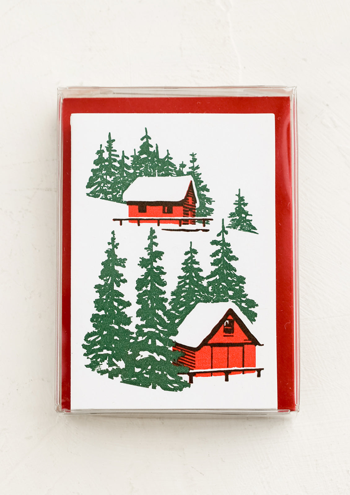 A set of letterpress mini enclosure cards with cabin in the woods print and red envelopes.