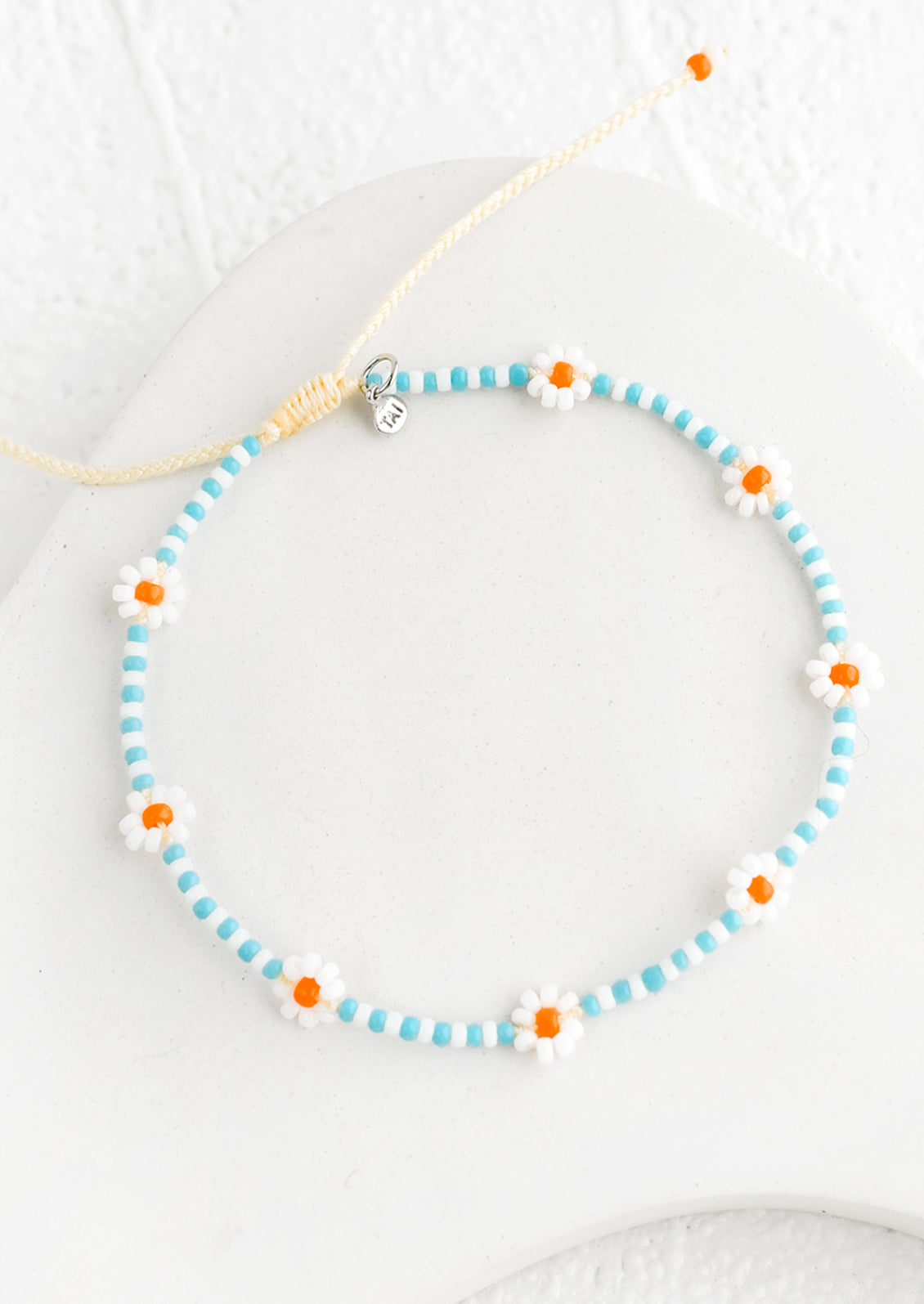 A beaded bracelet in blue and white with orange flowers.