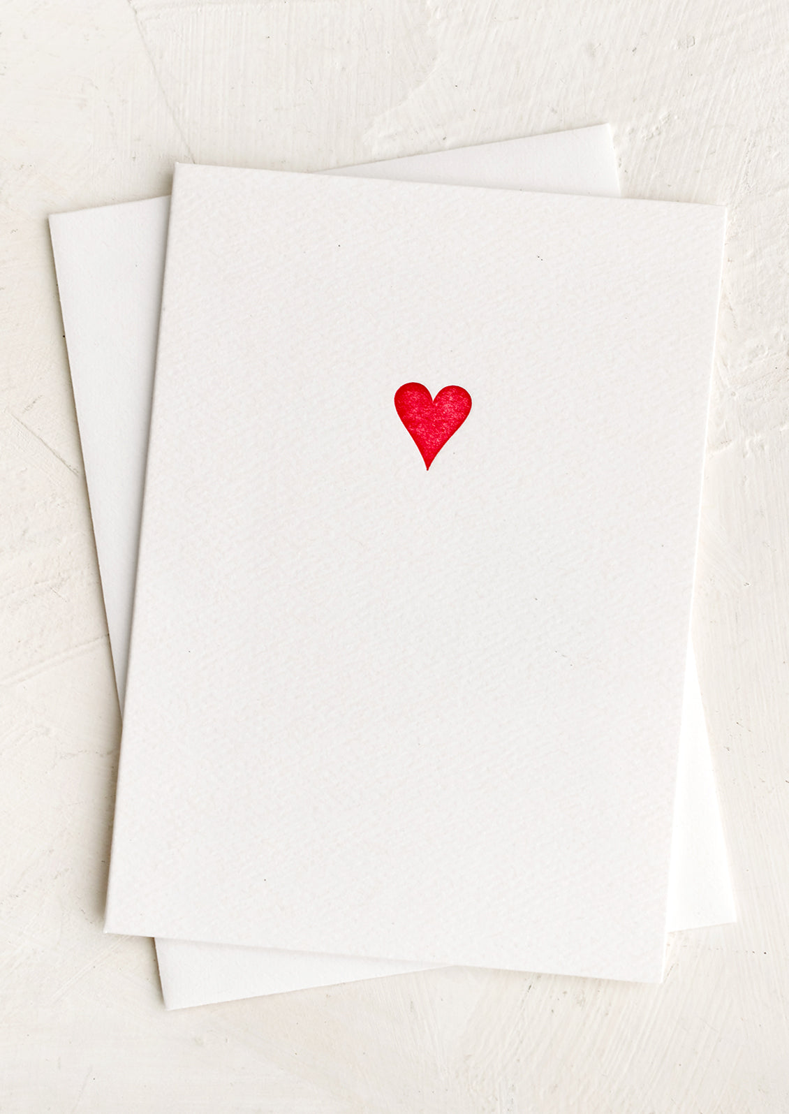 A plain white card with small red heart icon at front.