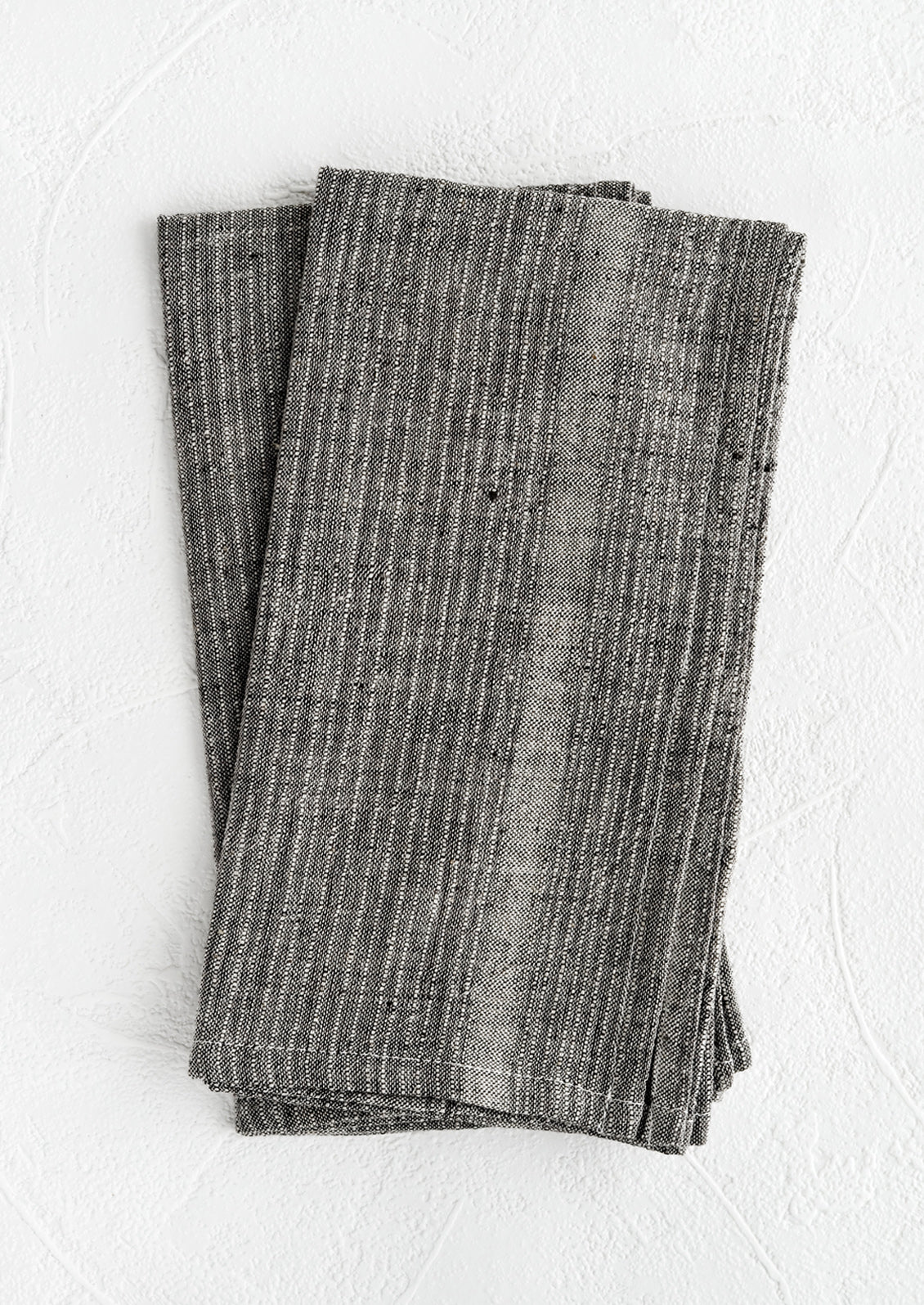A pair of charcoal fabric napkins with textured tonal stripe pattern.