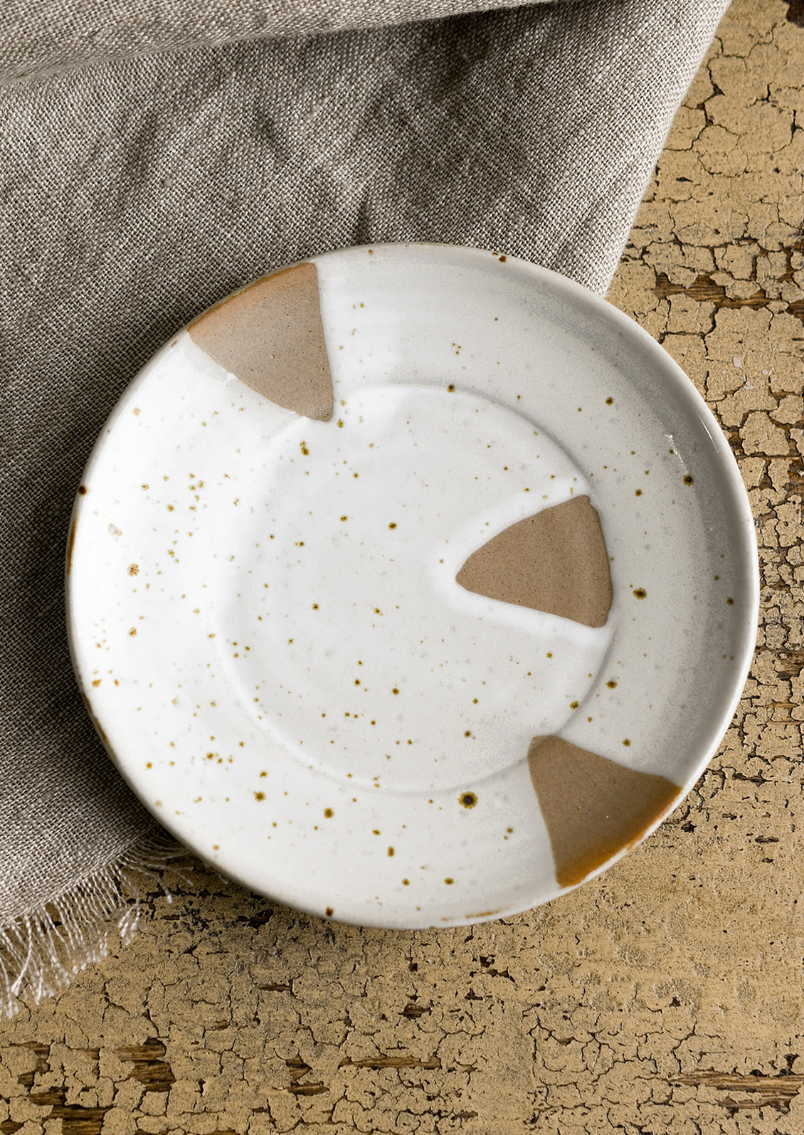 A small round saucer-like plate with brown and white triangle design.