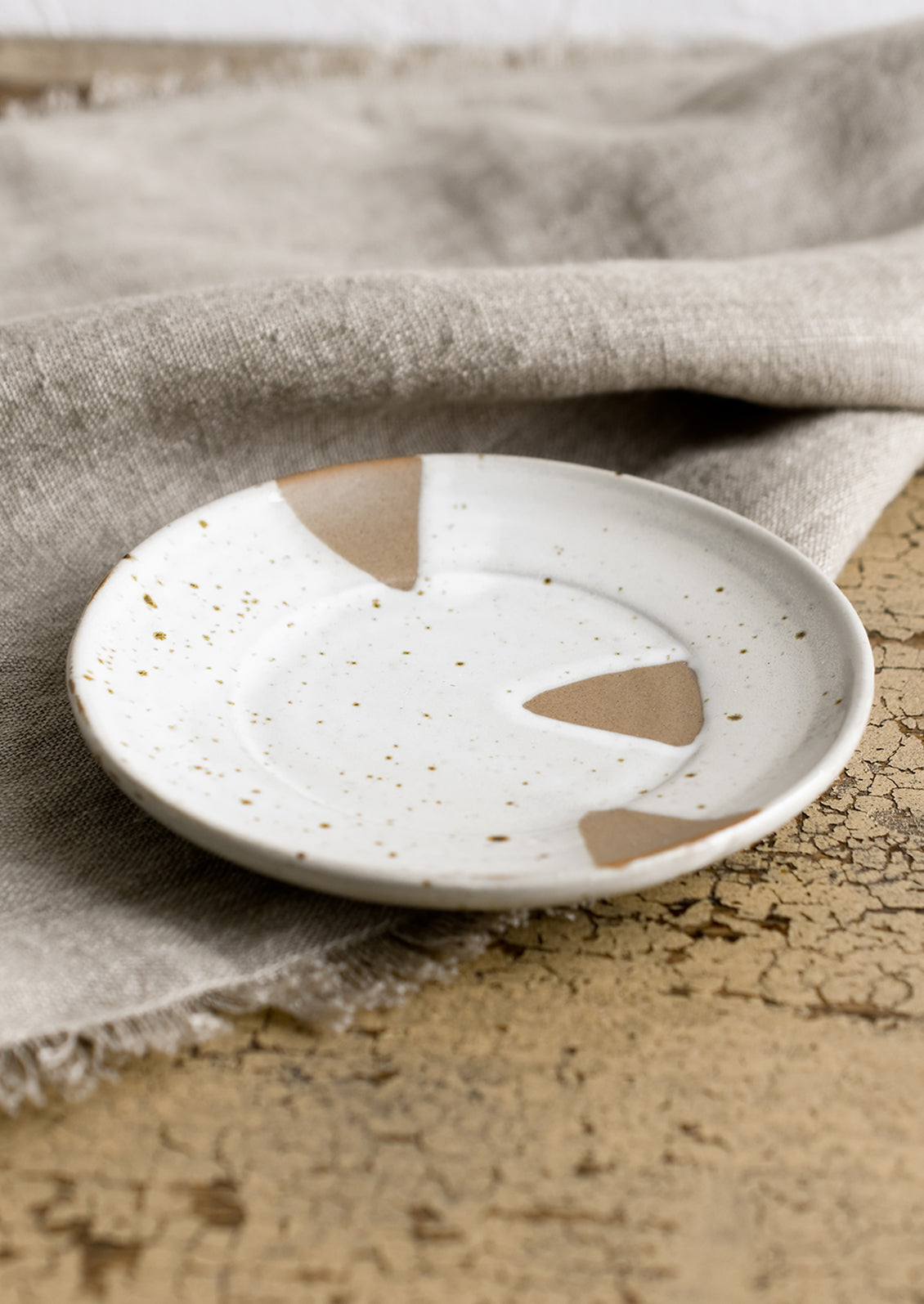 A small round saucer-like plate with brown and white triangle design.