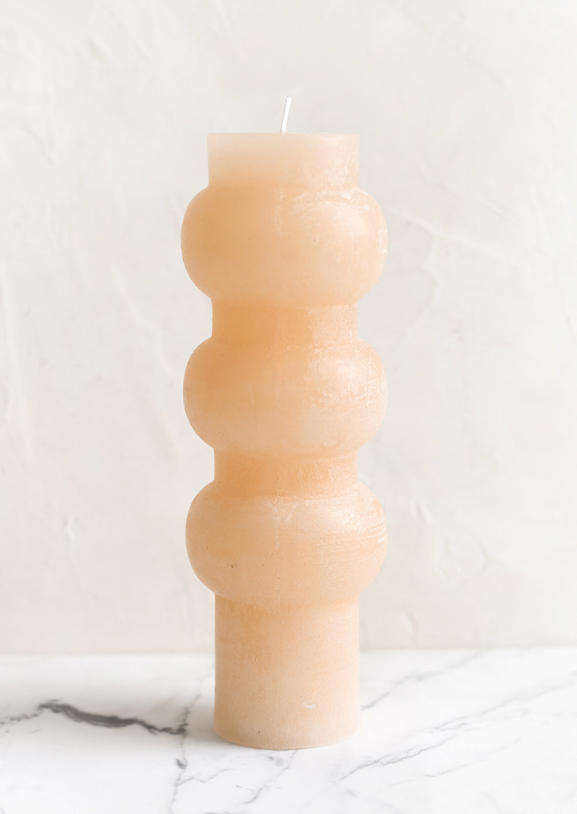 A large hourglass shaped pillar candle with waxy finish in petal.