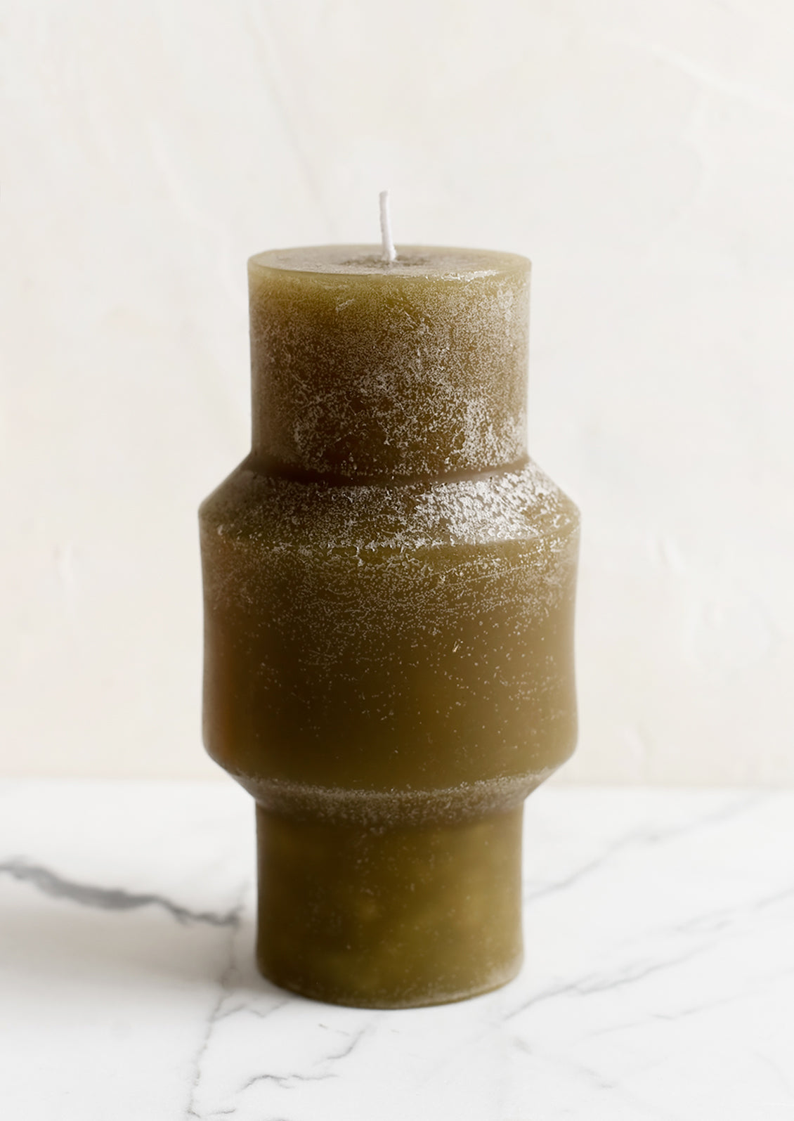 A medium carved pillar candle with waxy finish in olive.
