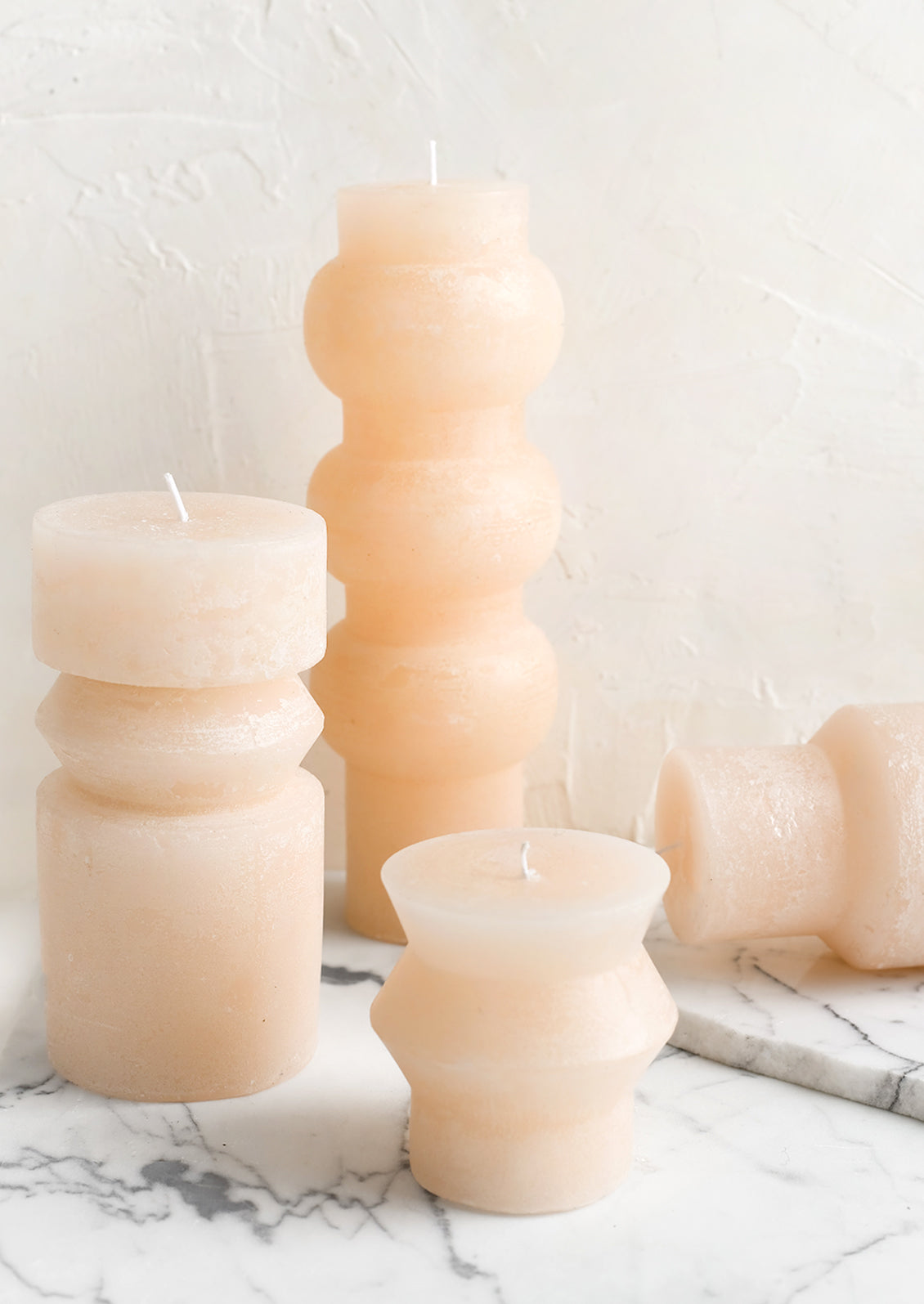 Assorted shapely pillar candles in petal light pink.