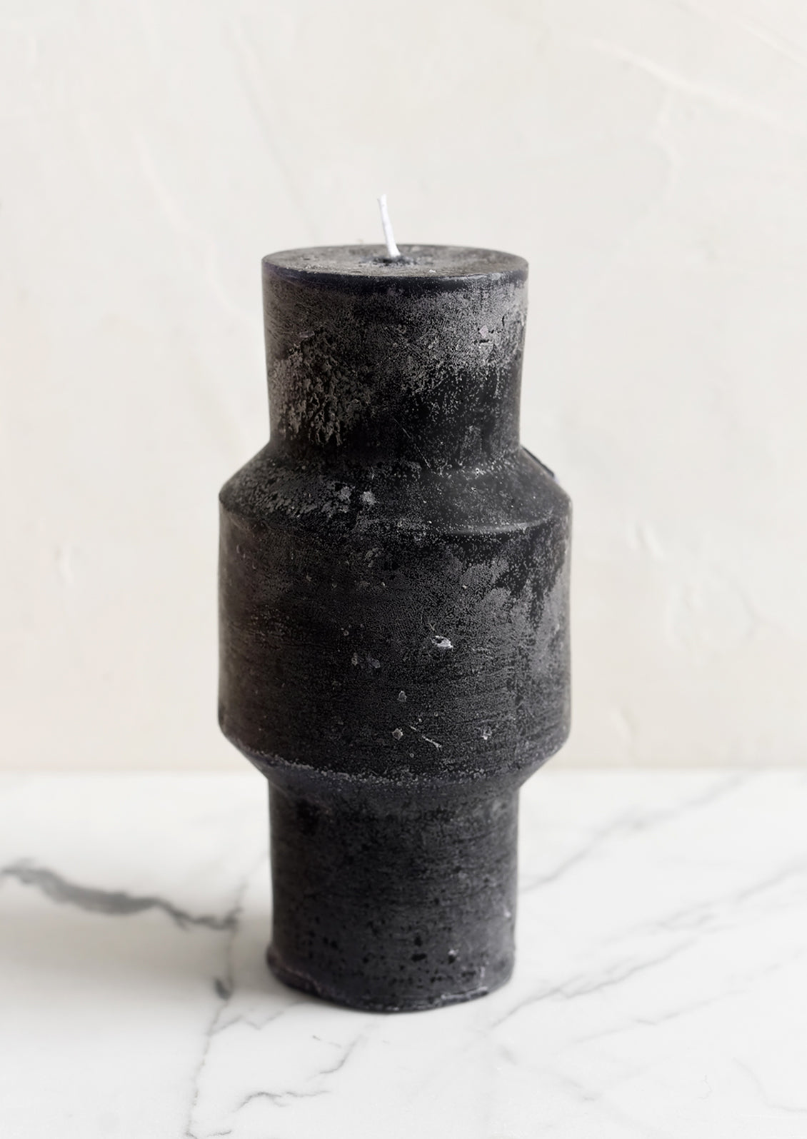 A medium carved pillar candle with waxy finish in black.