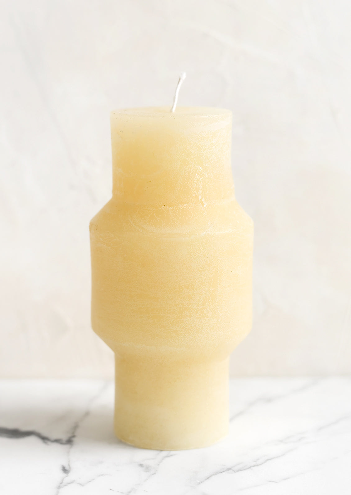 A medium carved pillar candle with waxy finish in vanilla.
