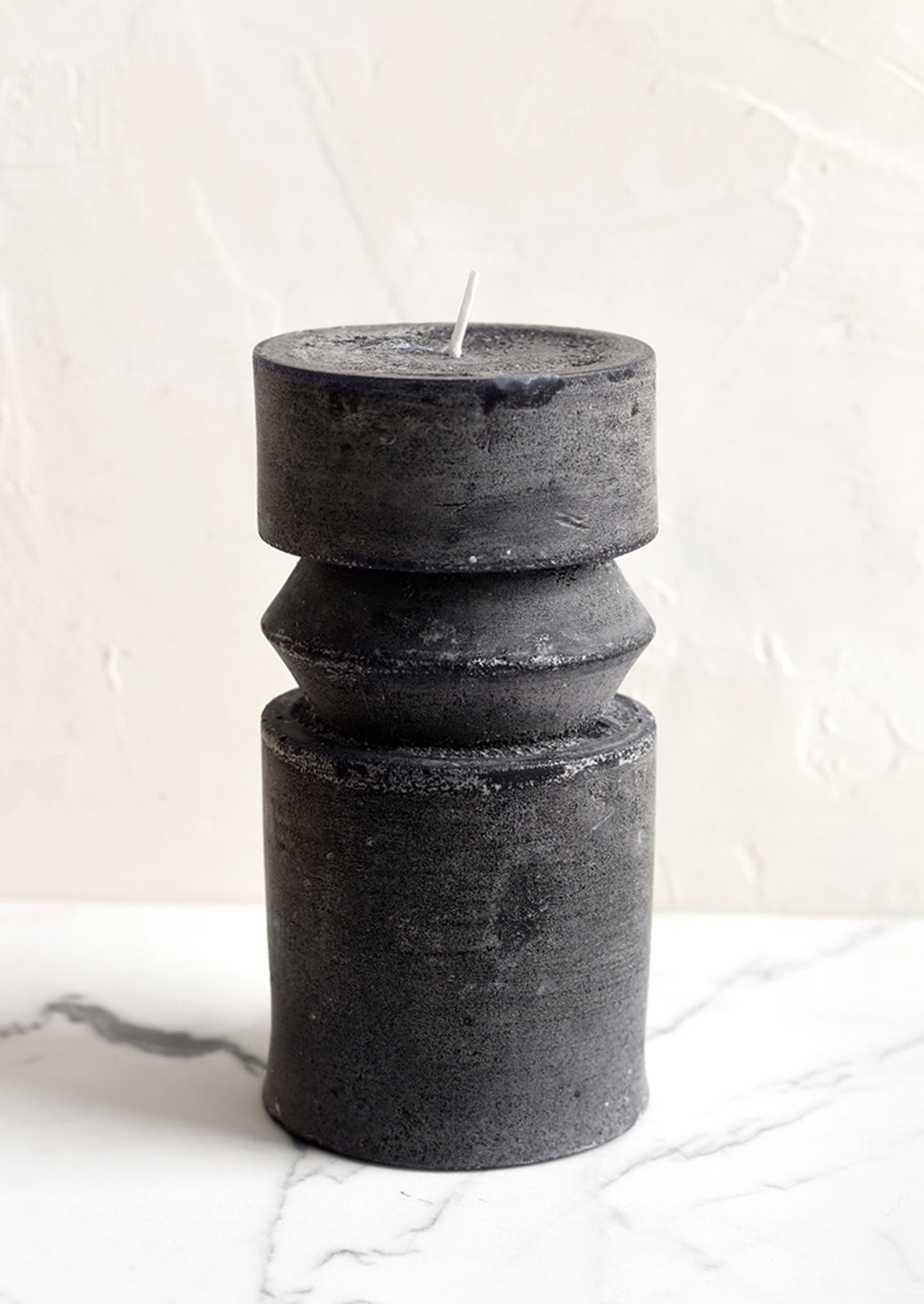 A medium carved pillar candle with waxy finish in black.