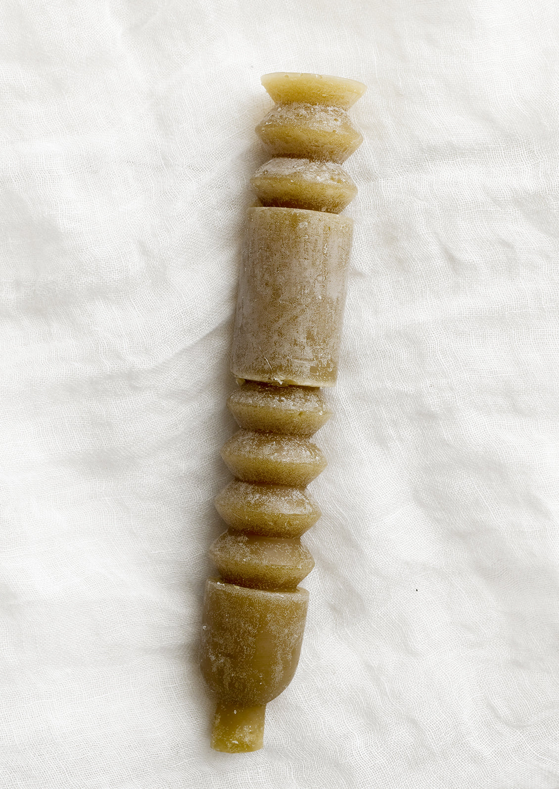 A geometric shape taper candle in olive.