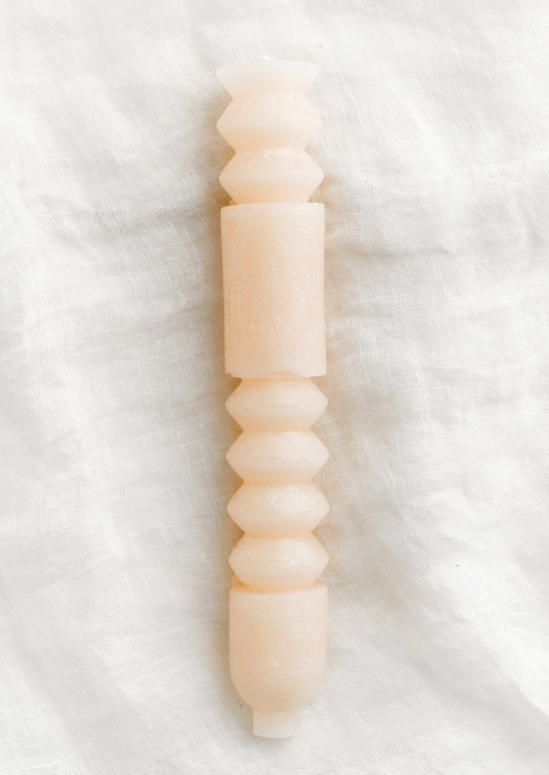 A geometric shape taper candle in petal (pale pink).