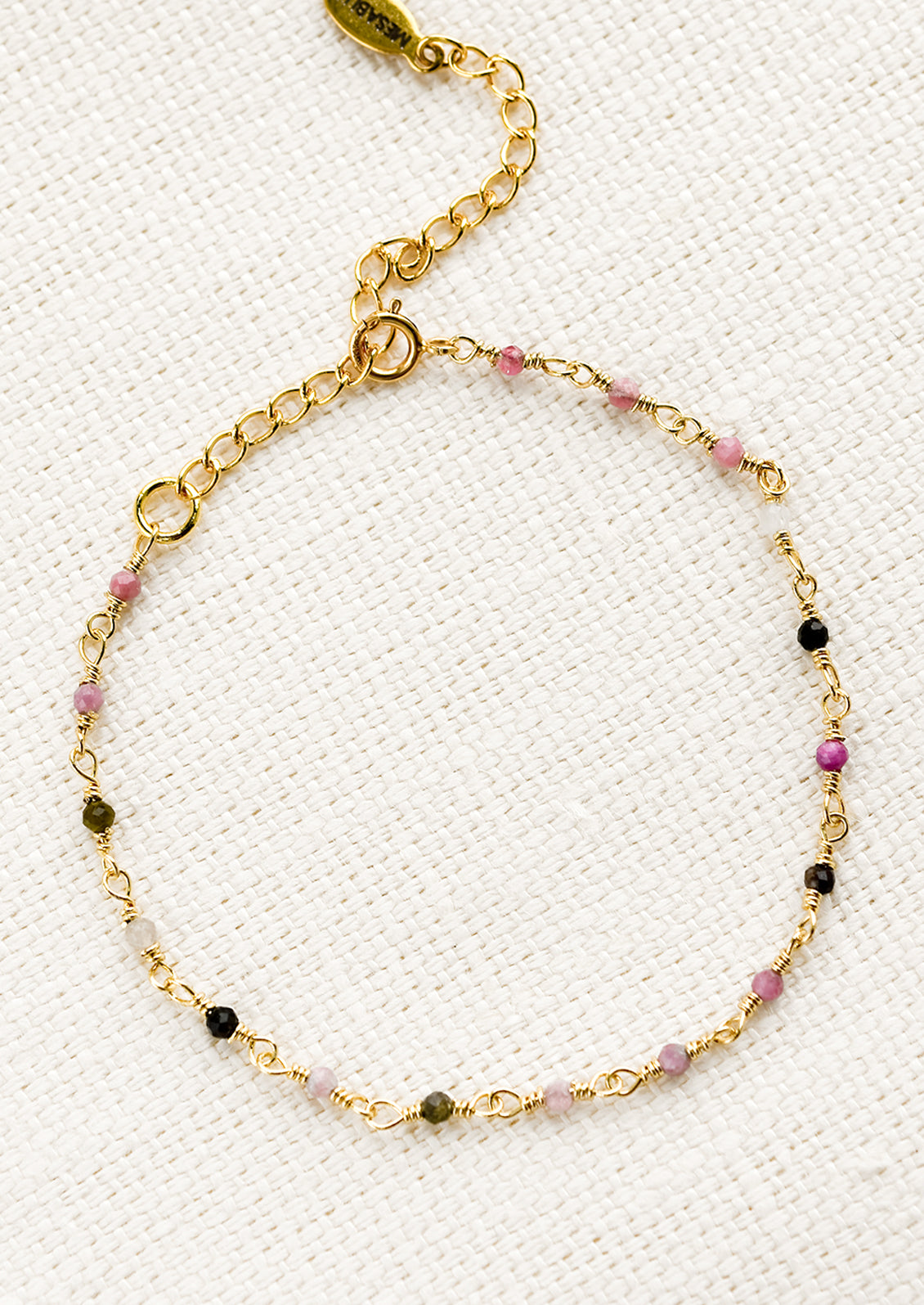 A gold wire bracelet with small multicolor tourmaline beads.