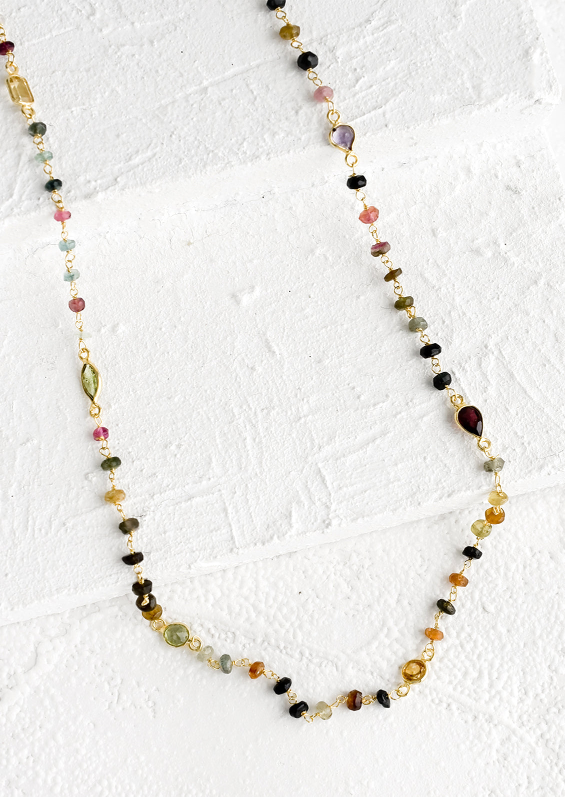 A long necklace with multicolor gemstones and tourmaline bezel.
