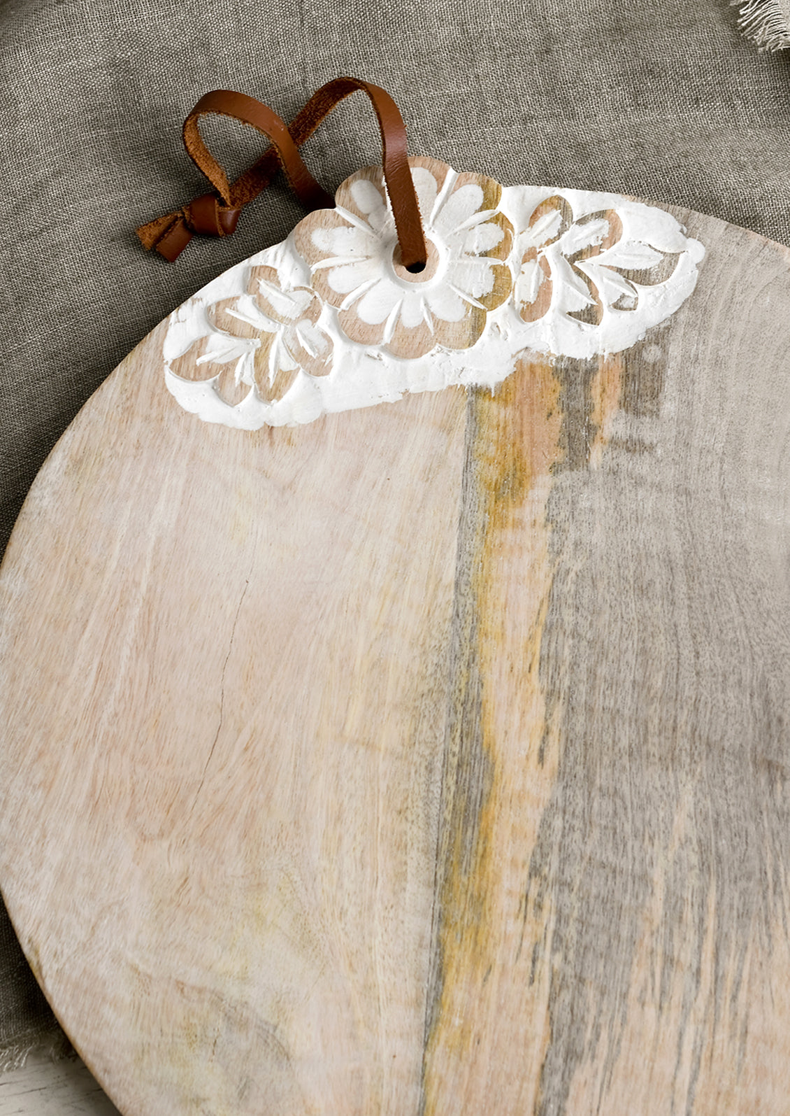 A round wooden cutting board with shabby chic floral detailing.