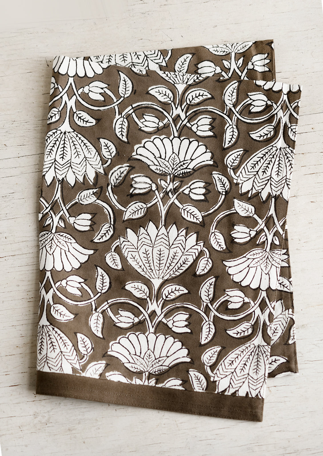 A dark brown and white lotus printed tea towel.