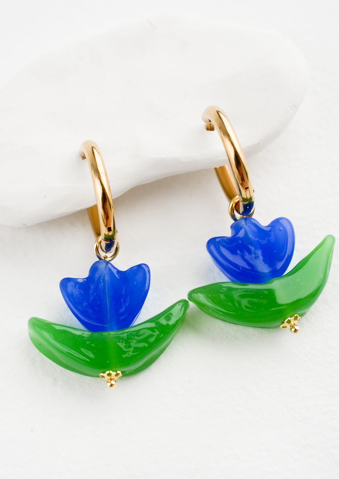 Glass earrings in the shape of a tulip in blue, with gold huggie hoop base.