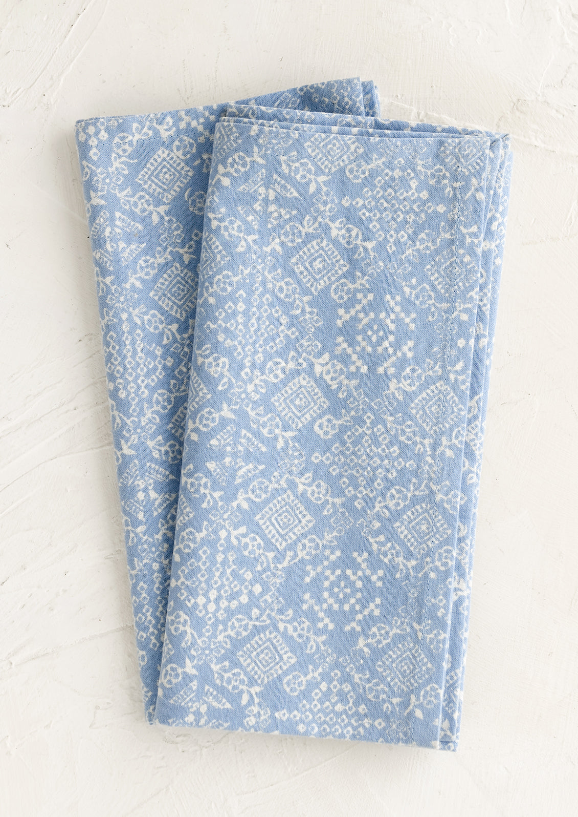 A pair of blue napkins with white tile print.