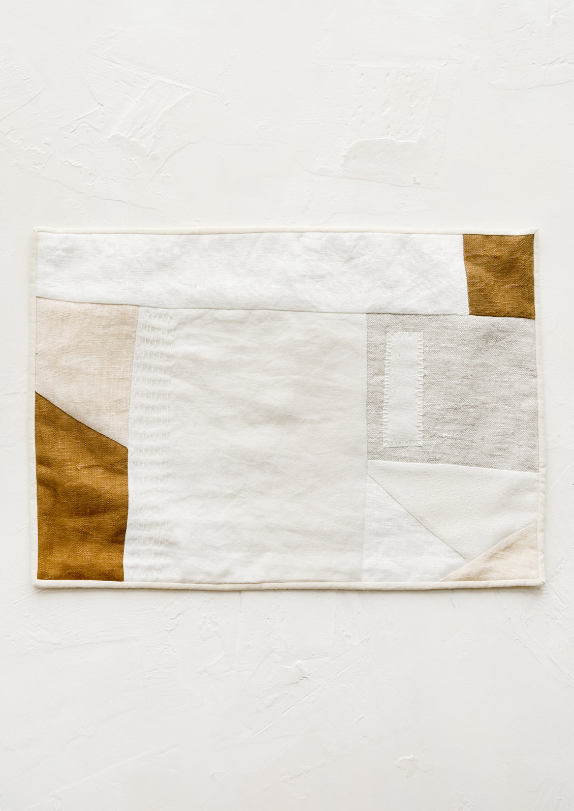 A rectangular placemat with patchwork design in natural shades.