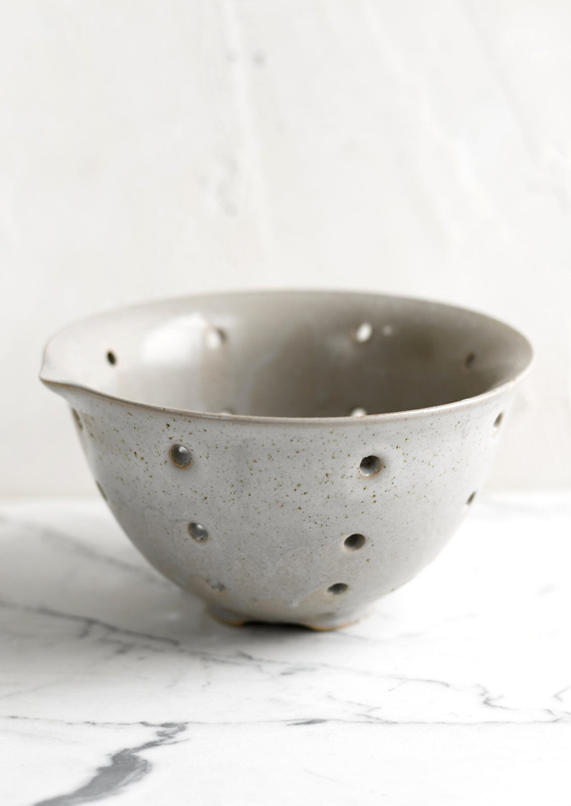 A greige ceramic stoneware colander.