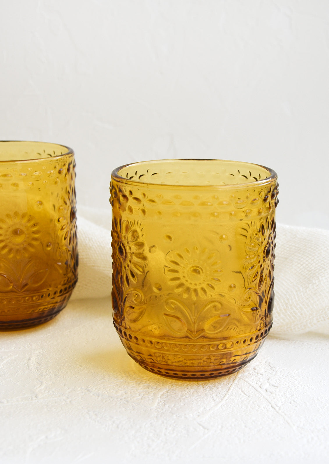 Two amber glass tumblers with floral embossed motif.