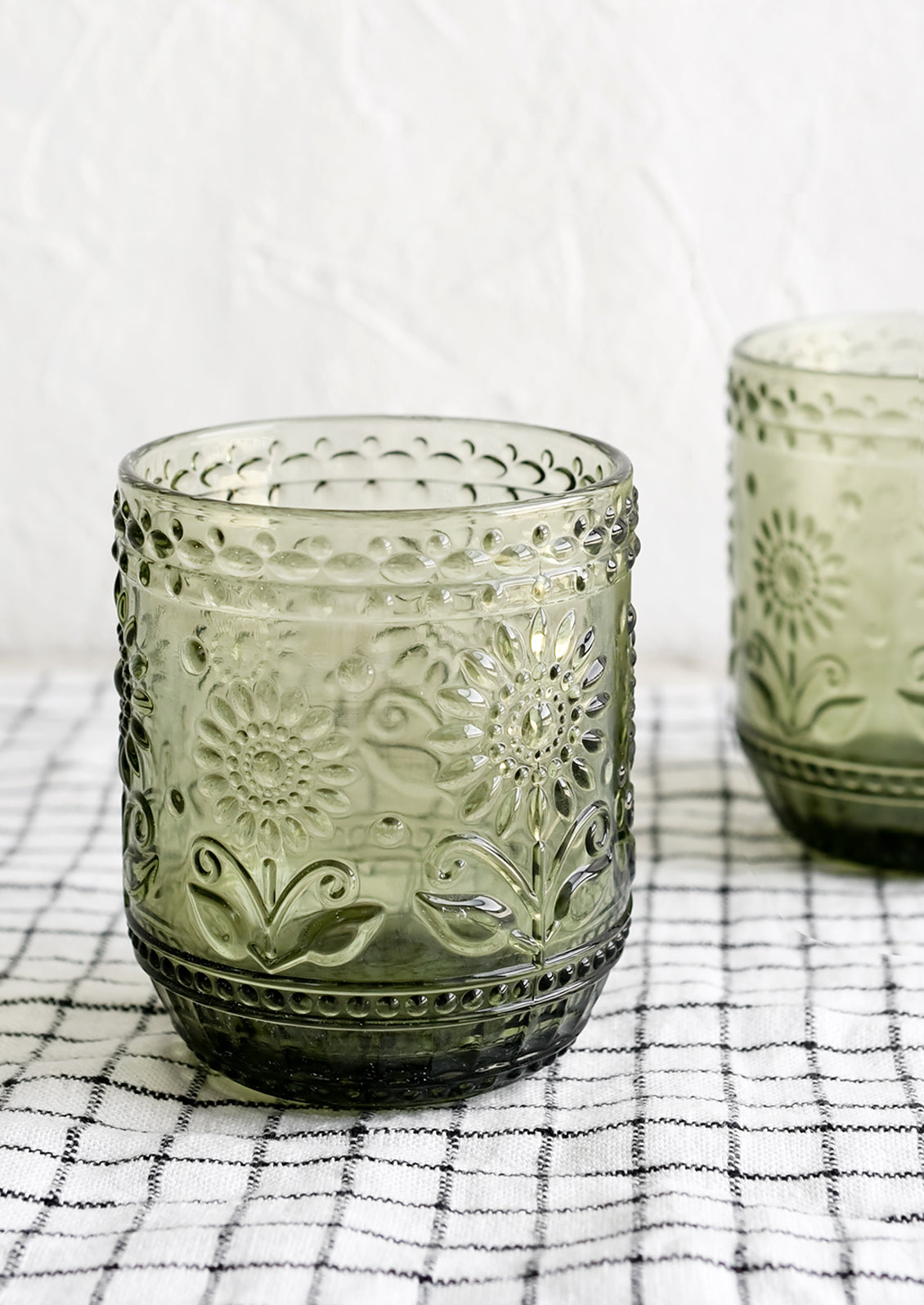 A pair of olive green glass tumblers with floral embossed motif.