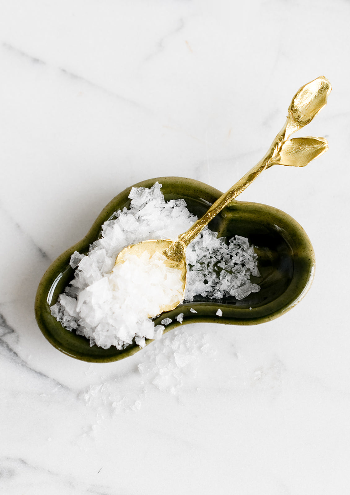 A small green ceramic dish with flaky sea salt.