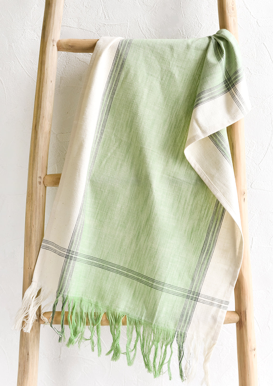 A green cotton tea towel draped over a ladder.