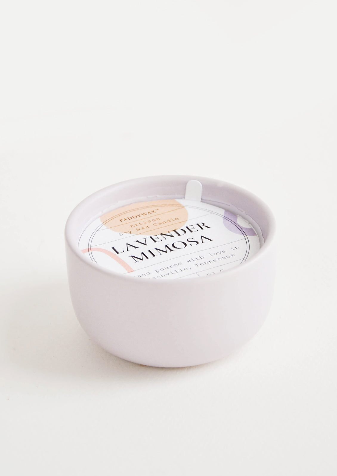Small scented candle in colorful pale lilac ceramic vessel