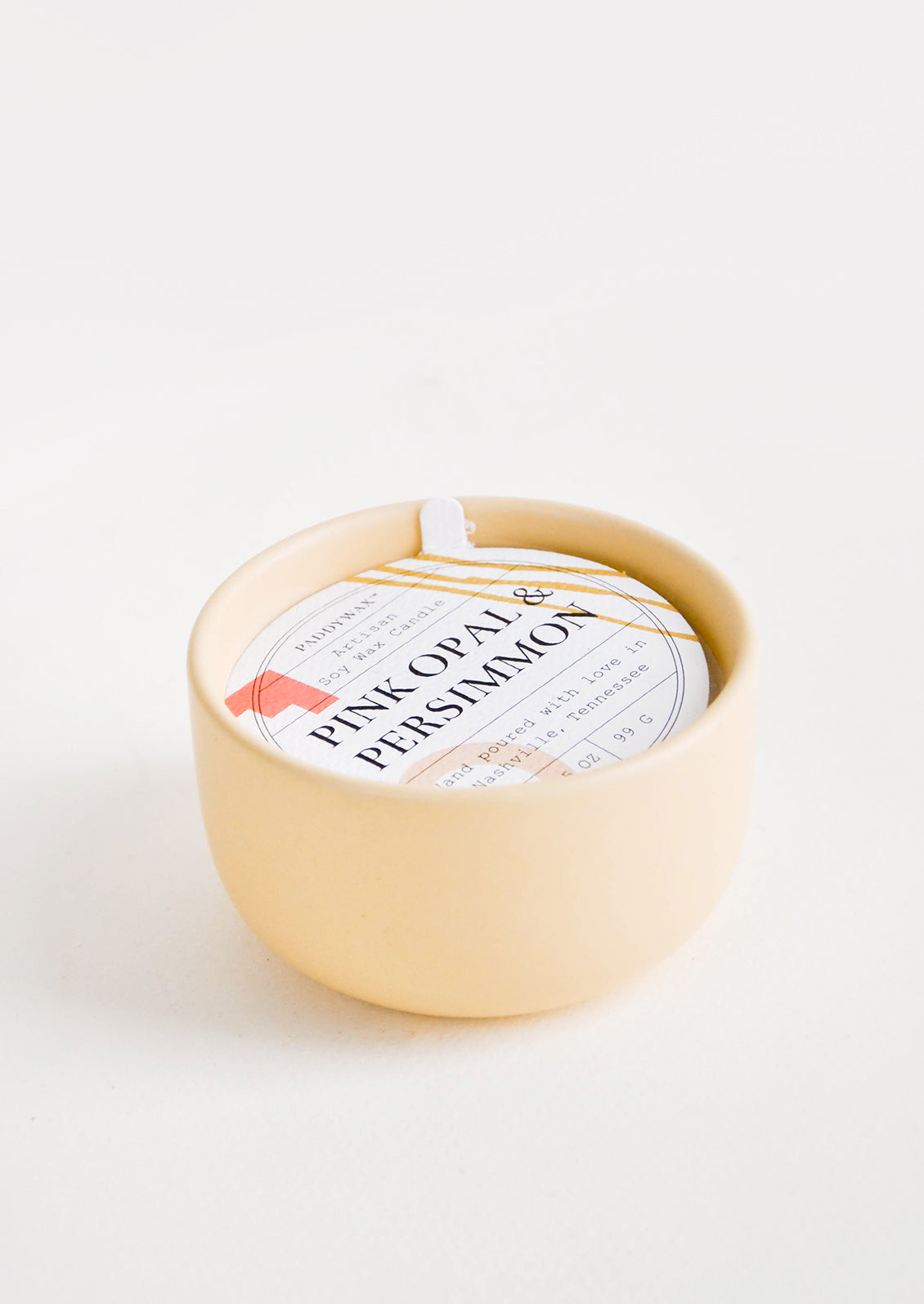 Small scented candle in colorful peach ceramic vessel