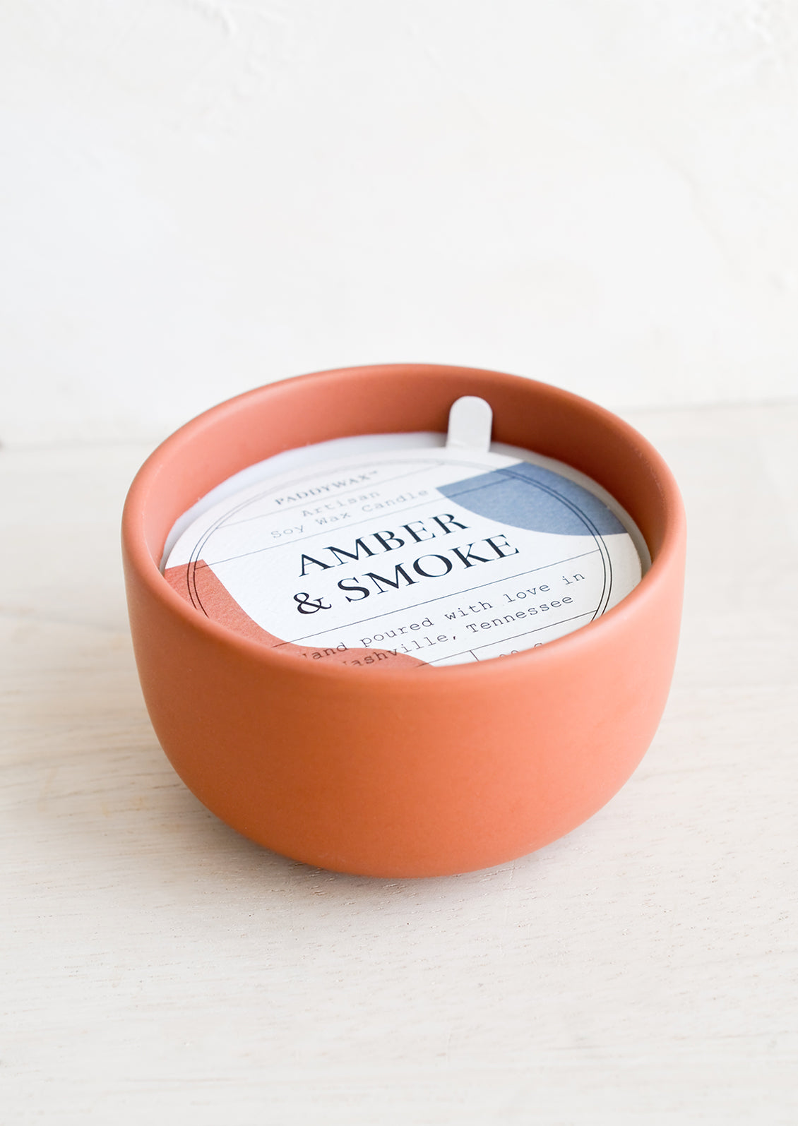 Small scented candle in colorful red ceramic vessel