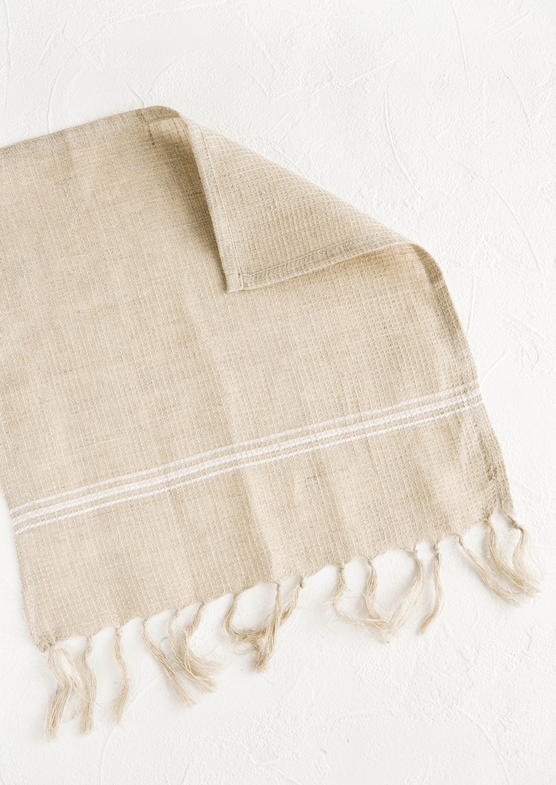 Waffle-textured dishcloths in natural color with single white stripe detail and tassel trim
